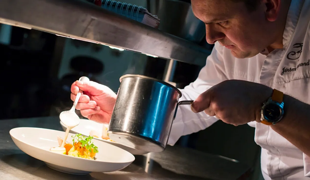 Chef ajoutant une sauce à un plat gastronomique raffiné